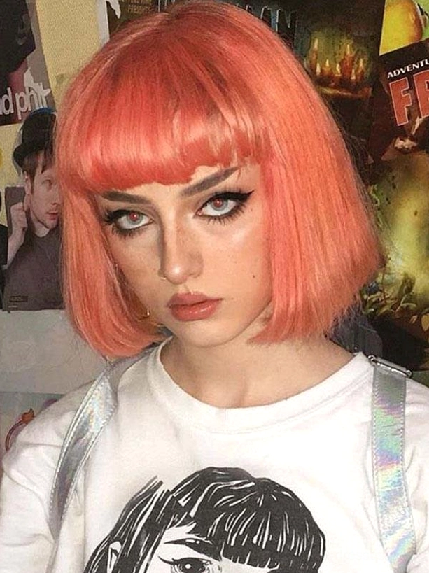 Coral orange vibrant short bob lolita wig with blunt bangs on model wearing printed casual tee, bright rococo-inspired sweet lolita front close-up