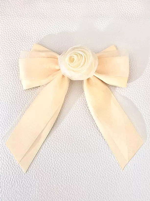 Cream beige sheer organza bow hair clip with cream rose embellishment, flat lay front view on white textured background, vintage-inspired sweet lolita accessory