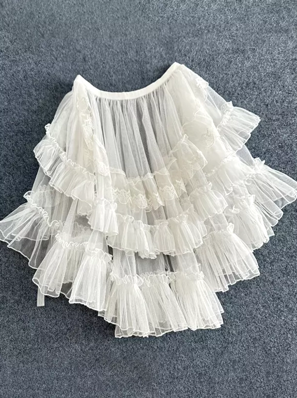 Cream lolita overskirt train with multi-layer ruffled tulle and delicate lace trim details shown in flat lay front perspective