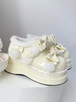 Cream white lolita platform snow boots with double front bows and pom-pom decorations, three-quarter view on white display stand