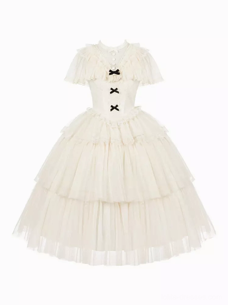 Flat lay standalone front view of cream white Lolita one-piece dress displaying cape collar, black bow trims, and dramatic tiered tulle skirt without model