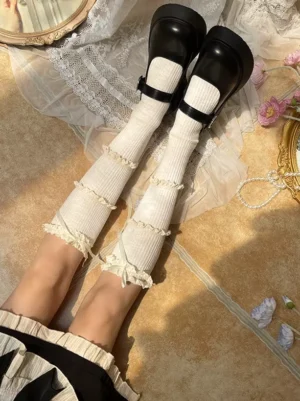 Cream white lolita over-the-knee stockings with white ruffle lace trim and bow worn with black platform shoes top-down view