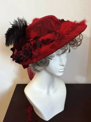 Deep crimson Victorian lolita wide-brim formal hat with black feather and red lace flowers right front view on mannequin with curly hair