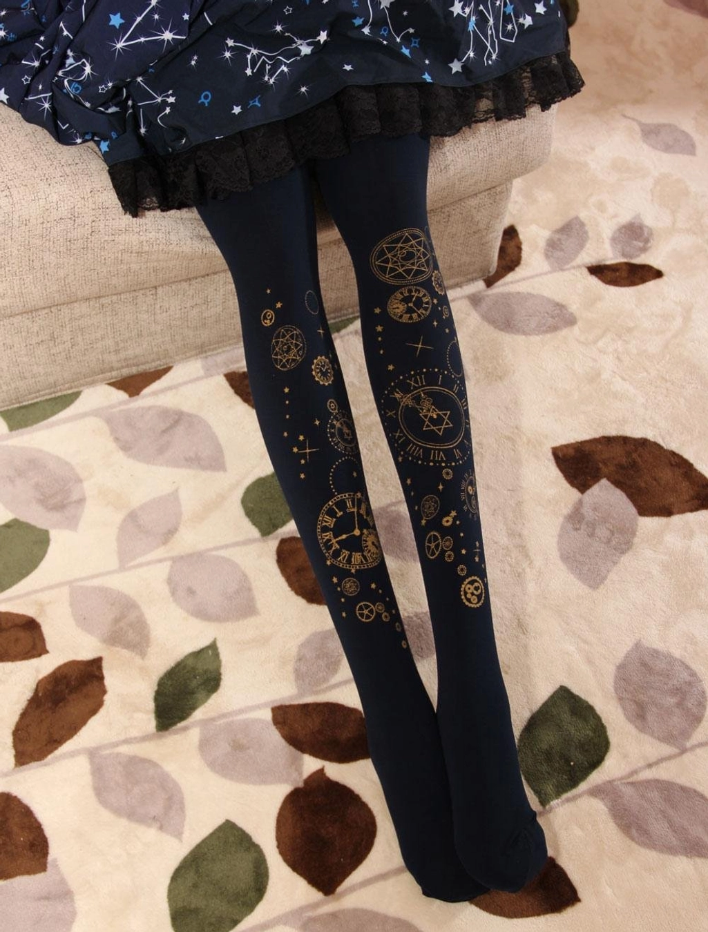 Dark blue velvet lolita pantyhose with gold foil steampunk gear and clock design, coordinated with star-patterned lolita skirt on sofa with leaf patterned carpet background