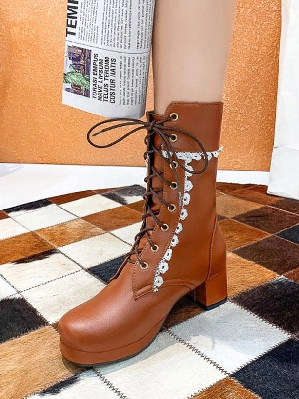 Dark brown lace-up Lolita ankle boots with round toe and chunky block heel adorned with white floral lace trim on cow print checkered floor