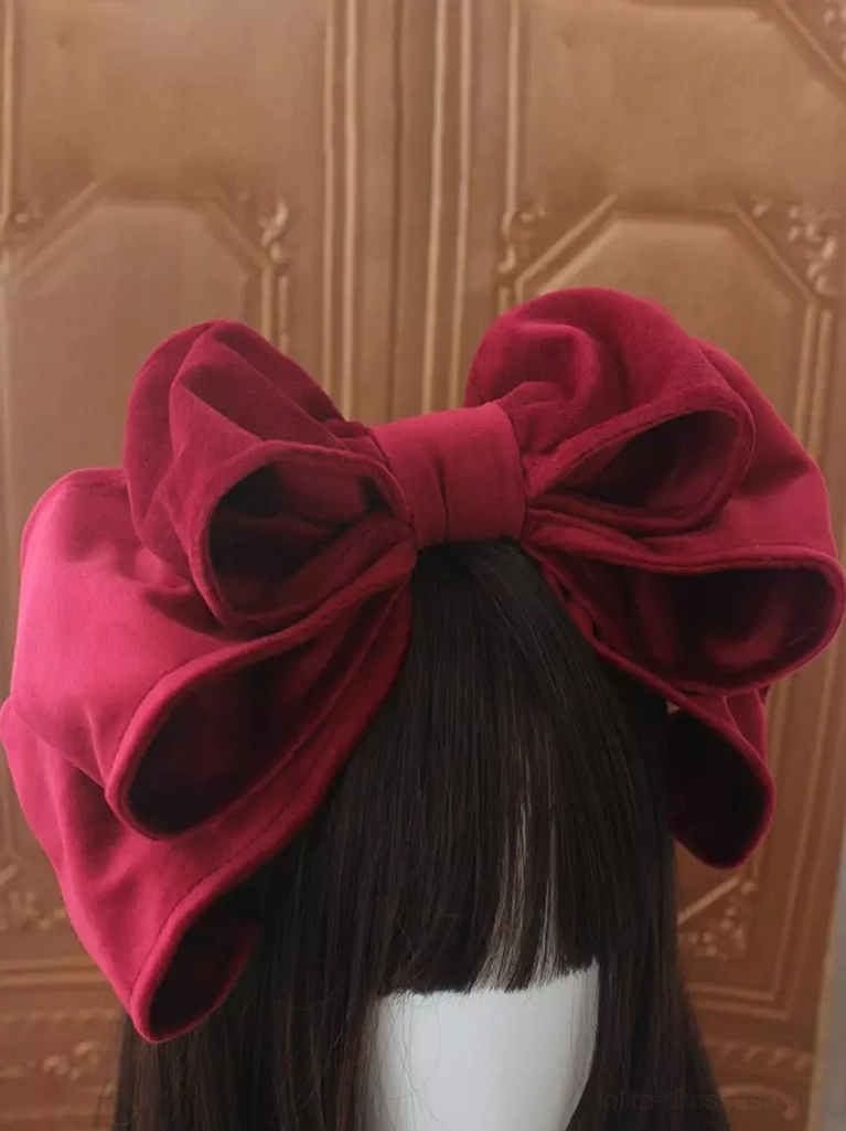 Dark rose red velvet Lolita bow headdress with double-layer construction displayed against carved wooden door background, showcasing rich color depth and dimensional bow structure