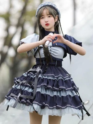 Deep blue sweet lolita 2-piece idol dress set front three-quarter view with navy and light blue two-tone pattern, puff sleeves, and ruffled tiered jumper skirt outdoor park setting