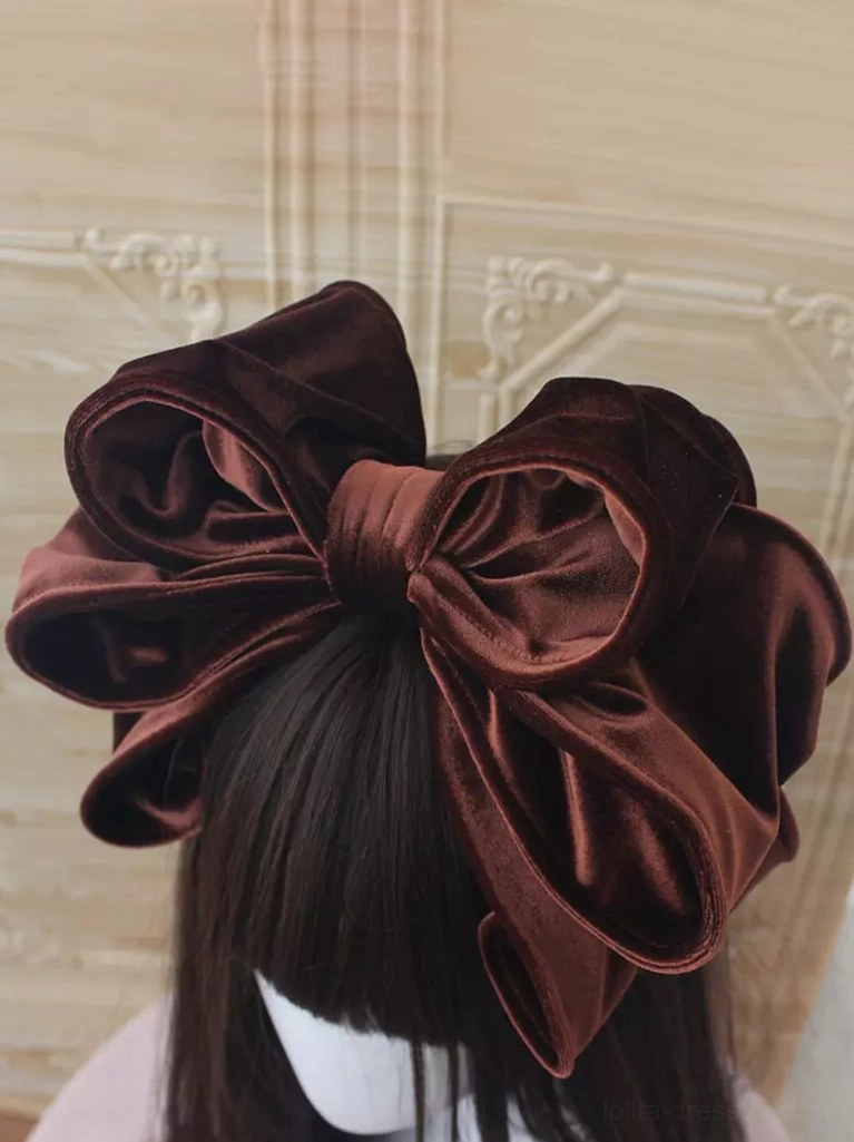 Deep brown chocolate velvet Lolita headdress showcasing oversized double-bow design on dark-haired mannequin, embossed decorative wall background creating elegant gothic-lolita atmosphere