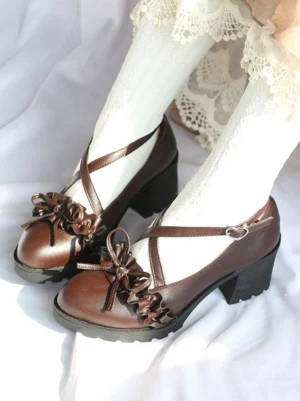 Deep brown Lolita leather shoes with cross strap ruffle bow detail, side overhead view showing model wearing feet with lace-trimmed white socks and Lolita skirt, chunky round block heel