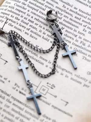 Double chain cross drop earrings displayed flat on vintage book paper, silver metal finish with three cross pendants per earring