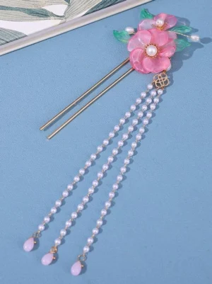 Dual gold metal hair stick hairpin with pink flowers and long pearl tassel drops, flat lay top view on light blue surface showing complete pearl tassel length and double stick construction