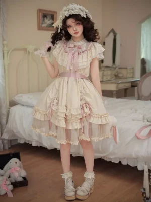 Ecru sweet lolita one-piece dress full front view worn on model in vintage bedroom setting, featuring layered lace ruffles, short ruffled sleeves, and pink ribbon waist sash accent