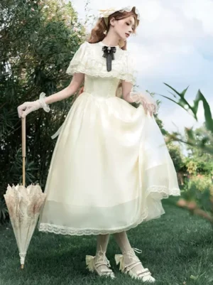 Ecru white hime sweet lolita midi dress with black bow cravat and short lace capelet, worn by model in garden setting, side front full-body view