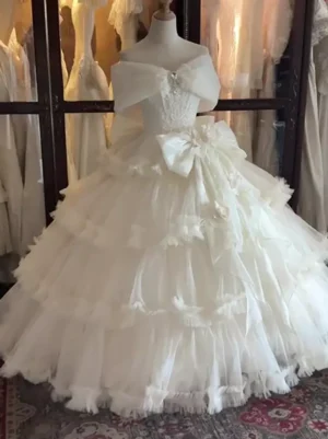 Elegant off-shoulder ballgown Lolita wedding dress with layered tulle skirt and bow design on mannequin