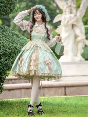 Mint green sweet lolita JSK dress with jacquard fabric front full-body view showcasing ruffled lace trim and pink bows in outdoor garden setting