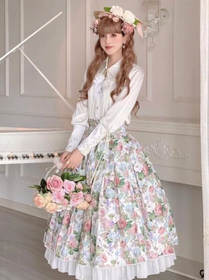 Floral print lolita skirt set three-quarter front view showing pink botanical pattern, white formal shirt, ruffle hem detailing, flower crown accessory, and flower bouquet, indoor piano background