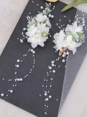 Floral pearl hair clip set with white and mint green flowers, pearl bead chains, and gold metal fasteners displayed on dark board with tulle - top-down flat lay view showing lolita accessory design details