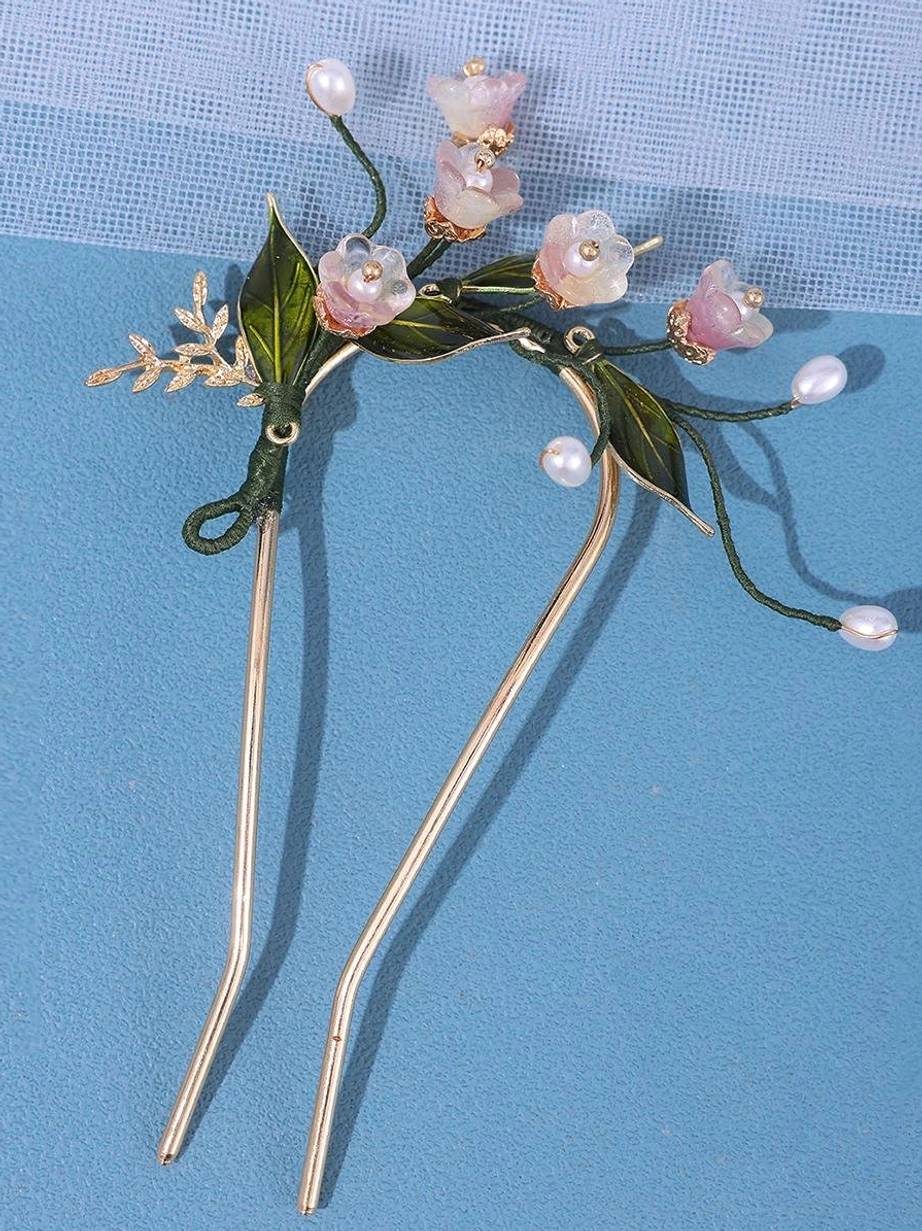 Ornate flower-themed U-shaped hair fork with faux pearl beads and pink resin blossoms featuring dark green wrapped wire joint on blue woven fabric backdrop, showcasing lolita accessory design