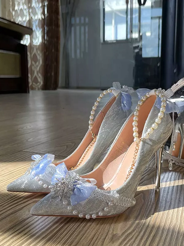 Pearl crystal glitter bridal stiletto pumps front three-quarter view with light blue tulle bow and pointed toe on wooden floor lolita wedding heels