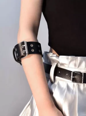Gothic black arm harness close-up showing double-row metal eyelets and rectangular silver fastener detail paired with elegant skirt