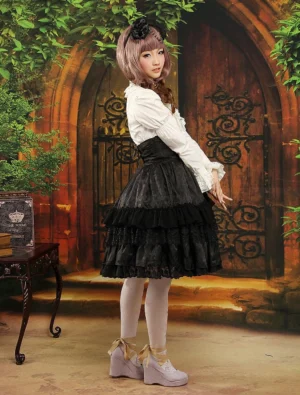 Gothic black ruffled lolita skirt side back angle showing high waisted silhouette, layered ruffle details, and A-line shape from vintage courtyard background