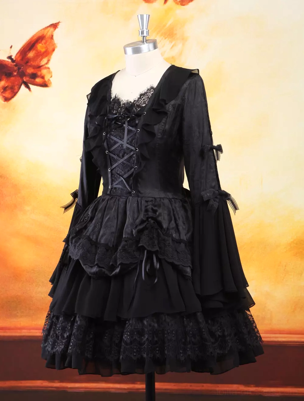 Angled front view on dress form showing gothic black lolita dress with tiered lace trim, multi-layered voluminous skirt, and structured bodice construction