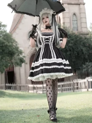 Gothic black and white lolita dress full front view on female model wearing argyle fishnet stockings and black parasol outdoor church setting square neckline white lace trim