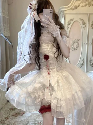 Gothic bridal Lolita dress front view on model wearing blood-stained veil, strapless corset bodice with rose bows, ruffled tulle skirt in vintage bedroom setting