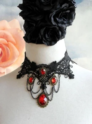 Victorian black lace choker with cascading red gems and vintage metal details against pink rose backdrop romantic gothic necklace