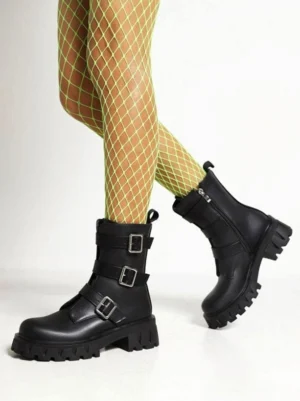 Black gothic metal buckle combat ankle boots front view showing triple metal buckle straps and chunky heel on model wearing neon green fishnet tights