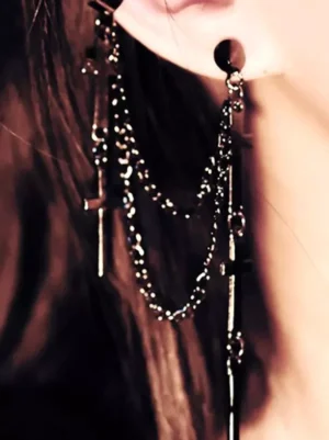 Gothic cross chain dangle earrings worn on female model ear, showing black silver layered chains with long cross pendants in close-up side view