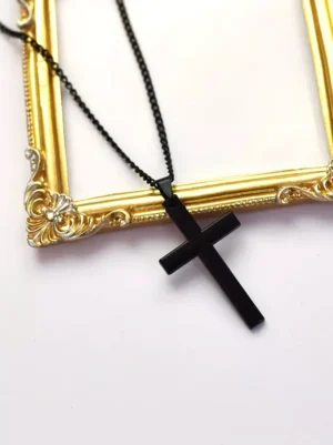 Matte black gothic cross pendant necklace with thin curb chain, displayed in vintage gold photo frame with elegant top-down view