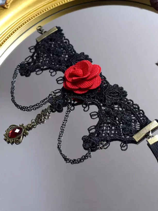 Gothic arm cuff flat lay display on round mirror, black lace with red fabric rose and red gemstone pendant, brass metal fasteners and chain visible