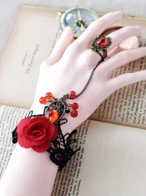Side view of gothic lace hand bracelet with ring chain, mannequin hand display, red rose and red gem decorations, linked wrist and finger ring connection