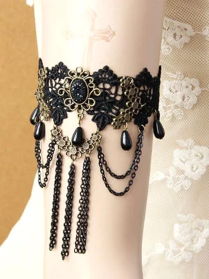 Black gothic lace leg garter with bronze metal ornaments and black teardrop beads worn on leg with chain tassels