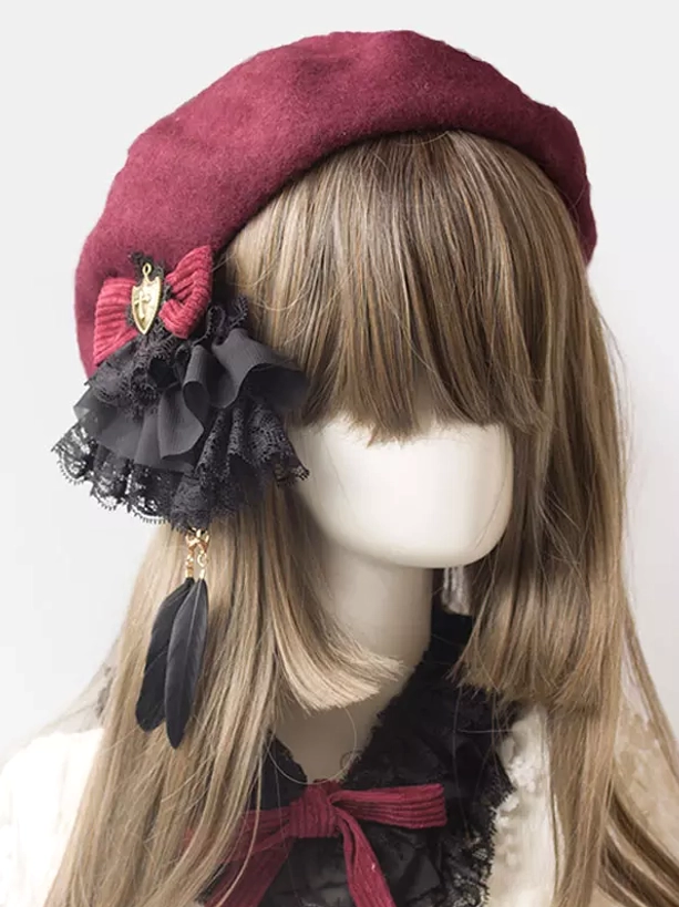 Gothic lolita beret hair accessory with wine red color and black lace ruffle detail, front half-face view on mannequin wearing style with feather pendant and metal shield charm