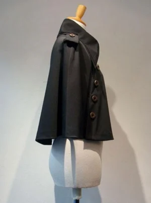 Gothic Lolita black cape left side view showing decorative button row placement along side seams, structured matte black silhouette, and professional styling on dress form for fashion photography