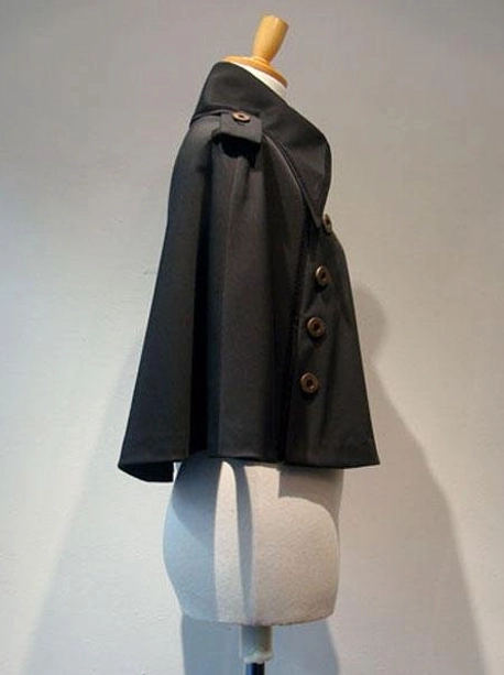 Gothic Lolita black cape left side view showing decorative button row placement along side seams, structured matte black silhouette, and professional styling on dress form for fashion photography