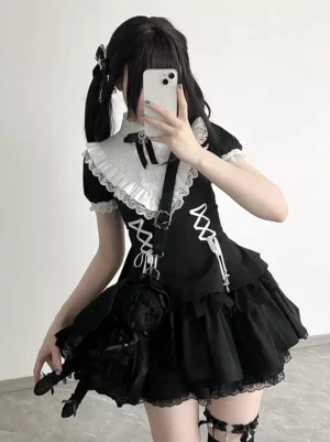 Black gothic lolita mini dress worn by model with twin-tails wearing black crossbody bag, front mirror selfie view showcasing lace-up corset front and tiered ruffles
