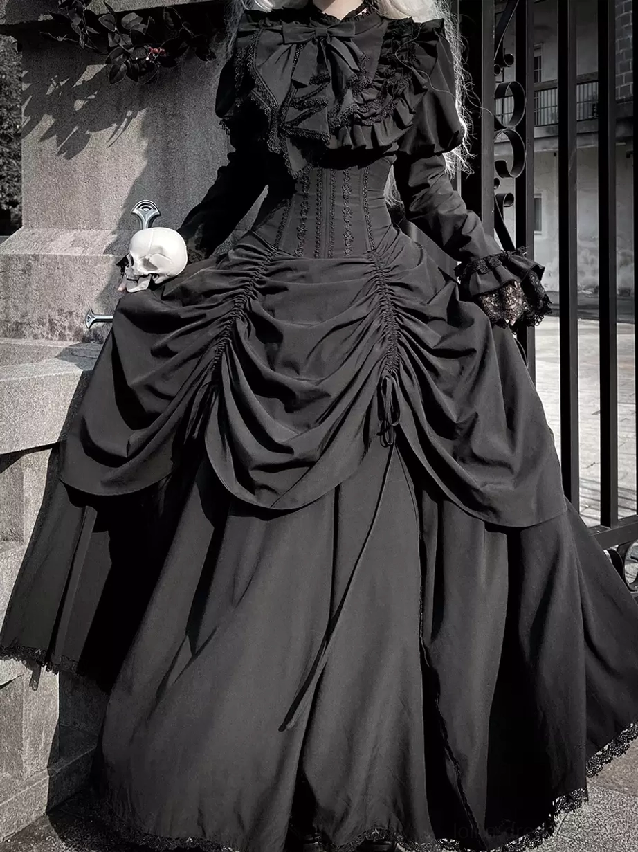 Gothic black lolita dress set full-body front view with ruffled collar and corset waist worn outdoors at vintage gate with skull prop