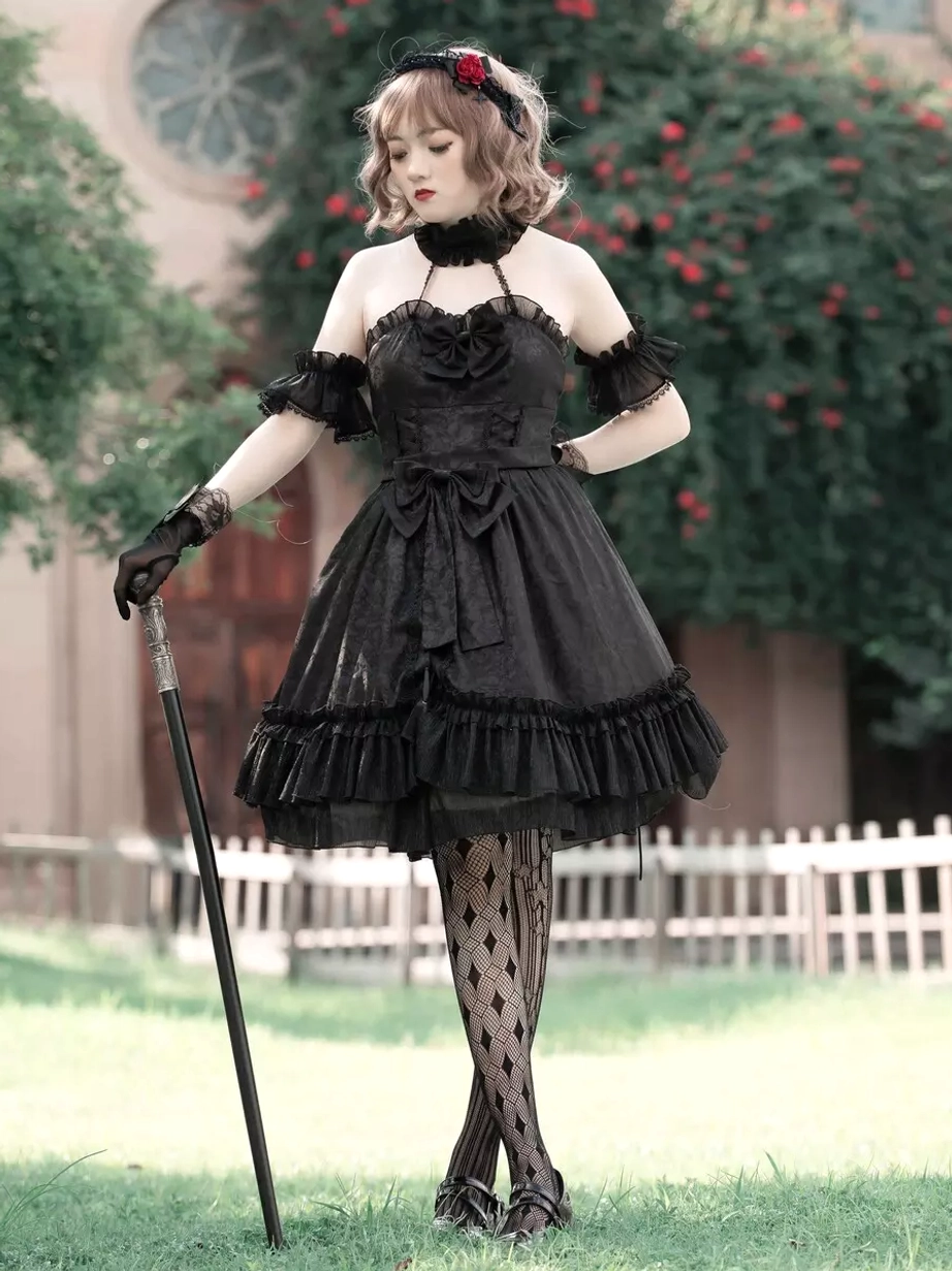Black Gothic Lolita dress side view showing halter neckline and lace gloves, diamond-patterned stockings with walking cane accessory