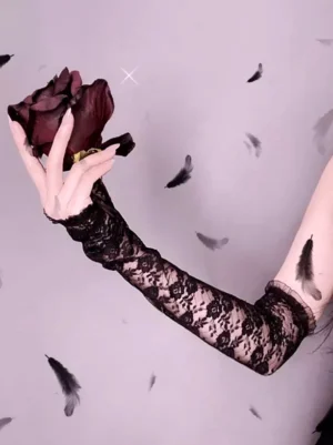 Close-up detail of black floral lace fingerless arm sleeve with decorative ruffled wrist edge trim, held by hand holding dark red rose, showcasing intricate lace pattern and Gothic aesthetic