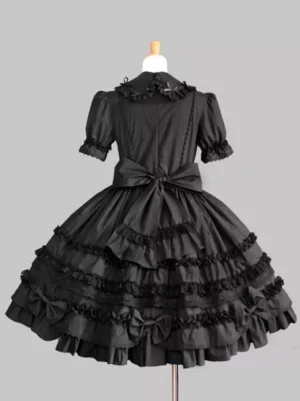Gothic lolita dress black back view showing large back bow, multi-layered ruffled skirt, ruffled doll collar, and structured silhouette on dress form