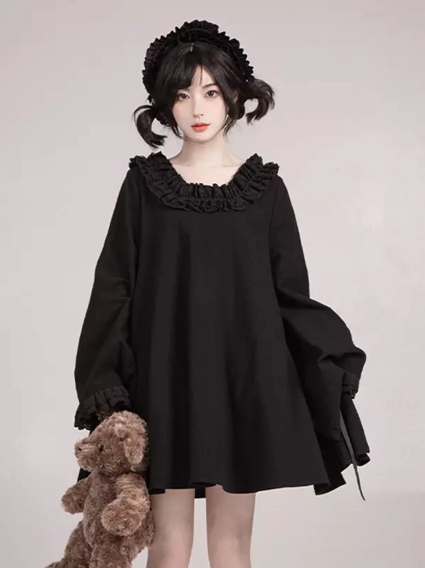 Front view of solid black ruffled Gothic Lolita dress with loose A-line silhouette, wide bell sleeves, and teddy bear accessory styling