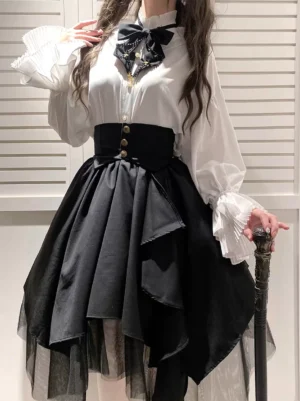 Gothic lolita black tiered skirt with gold buttons front view close-up showing asymmetrical layered tulle hem and high waistline worn with white ruffled blouse and bow tie
