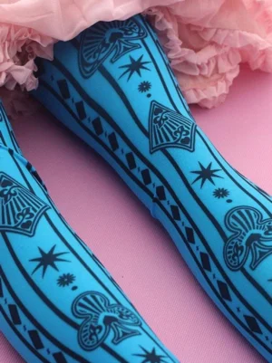 Gothic Lolita blue printed stockings side close-up view showing black star fan and stripe patterns on legs with pink ruffled skirt