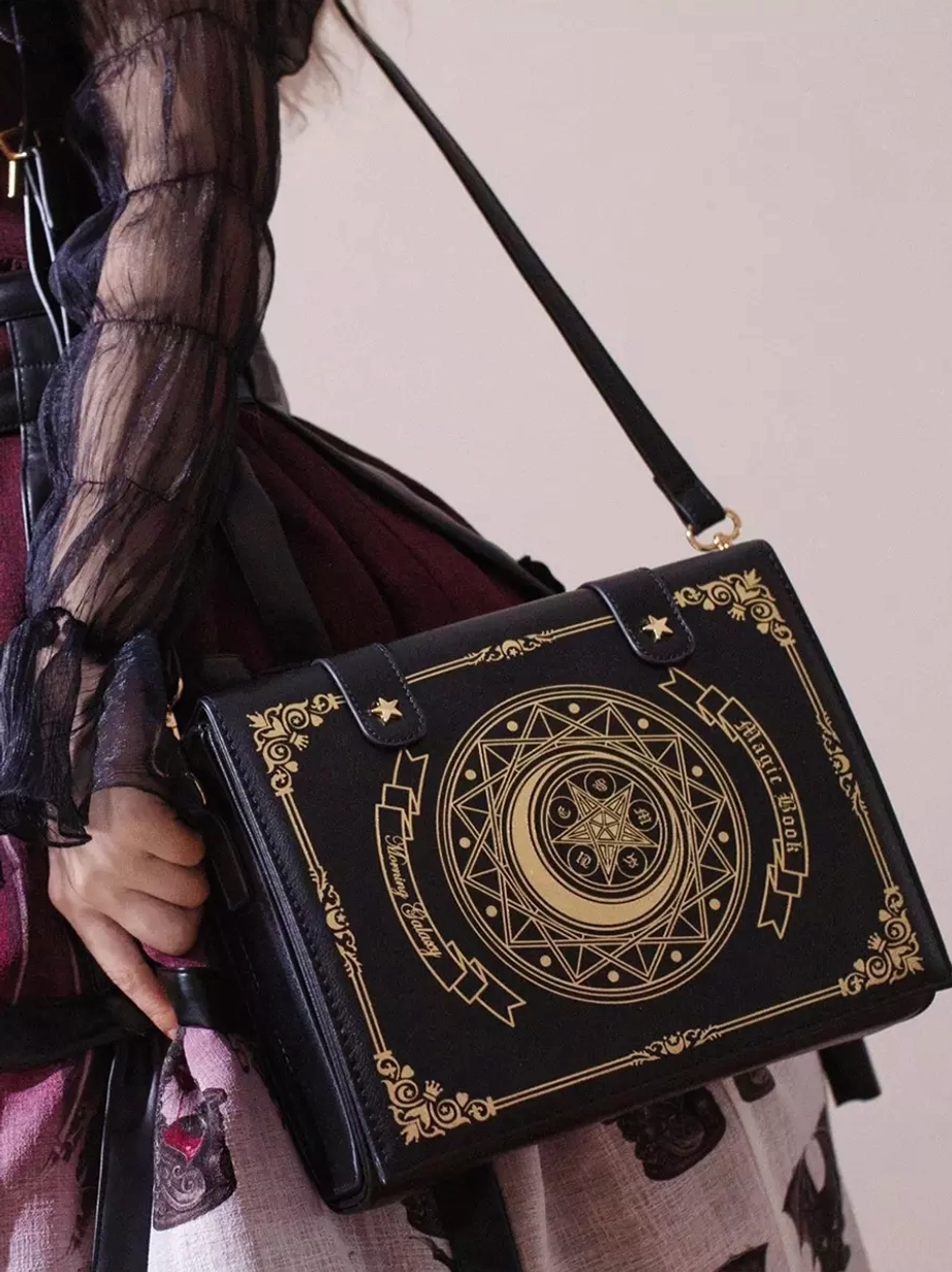 Close-up detail of Gothic Lolita book-style bag showing adjustable leather shoulder strap and intricate golden moon star magical pattern on black base