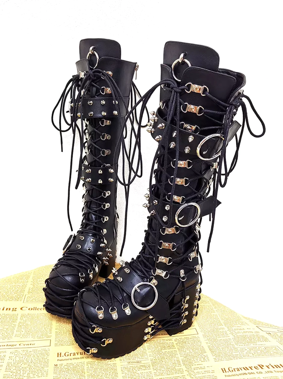 gothic lolita boots left side angled view showing silver stud and buckle decorations lace-up front design thick wedge heel vintage newspaper background