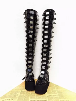 Front view of over-the-knee gothic platform lolita boots highlighting square silver metal trims and rectangular buckles along the shaft with thick matte wedge sole