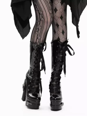 Gothic lolita patent leather platform boots front view featuring ribbon lace-up closure with metal grommets, chunky block heel, glossy finish, styled with black ruffled skirt and fishnet stockings